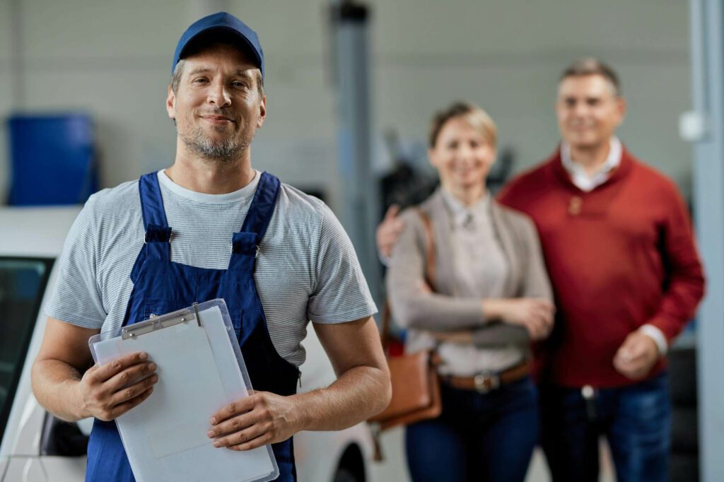 portrait-happy-auto-repairman-looking-camera-while-his-customers-are-standing-background